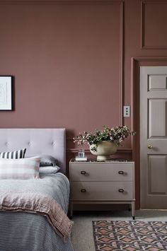 a bedroom with pink walls and white furniture