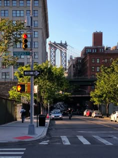 an intersection with traffic lights, cars and people walking on the sidewalk in front of tall buildings