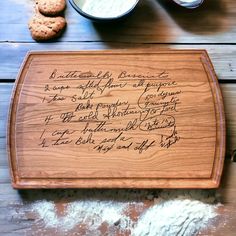 a wooden cutting board with writing on it next to some cookies and other food items