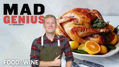 a man standing in front of a turkey on a plate with oranges and greens