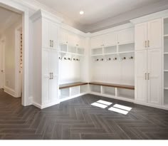 an empty room with white cupboards and shelves on the wall next to a wooden floor