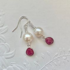 Sterling silver Pearl and Ruby earrings featuring sterling silver bezel set genuine faceted Rubies and beautiful high lustre white nucleated Pearls. I have finished the earrings with 925 sterling silver shepherd hooks and findings. A stunning pair of earrings that will make a perfect gift for June or July babies as Ruby is July's birthstone and Pearls are one of June's birthstones. * The Ruby bezels measures approximately 12mm x 8mm. * The nucleated pearls measure approximately 9mm x 9mm. * The White Gemstone Jewelry For Mother's Day, Elegant White Jewelry For Birthday, Elegant Pearl Drop Jewelry For Birthday, Hypoallergenic Briolette Earrings As A Gift, Hypoallergenic Briolette Earrings For Gift, White Sterling Silver Earrings For Birthday, White Teardrop Earrings For Mother's Day, Handmade Briolette Earrings For Anniversary, White Sterling Silver Pearl Earrings For Anniversary