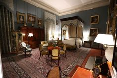 a bedroom with blue walls and carpeted flooring, furniture and paintings on the wall