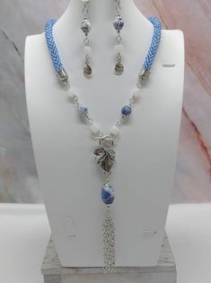 "Handmade and designed by me-one of a kind necklace set-blue seed bead crocheted rope necklace-22\" long-2 1/2\" long chain tassel with a sodalite nugget-sodalite accent beads-matte frosted dragon vein agate cube beads-metsl beads-3 1/4\" long dangle earrings with a flower charm-antique silver tone leaf toggle clasp in front-antique silver tone findings. Make this unique necklace set a great addition to your jewelry collection! Would make a statement when adding to your summer outfit!" Blue Macrame Jewelry With Round Beads, Crochet Gemstone, Necklace Matching, Bead Crochet Rope, Dragon Vein Agate, Crochet Rope, Earrings Pendant, Long Dangle Earrings, Rope Necklace