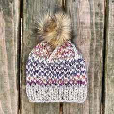 a multicolored knit hat with a pom - pom on the top