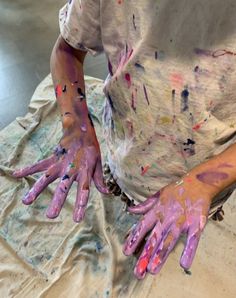 two hands covered in paint sitting on top of a table