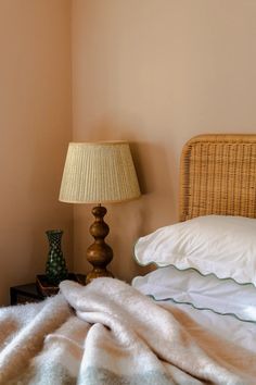 a bedroom with a bed, lamp and wicker headboard on the side table