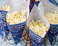 four blue paper cones filled with popcorn on top of a table