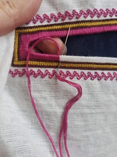 someone is stitching something on the side of a piece of cloth with pink thread