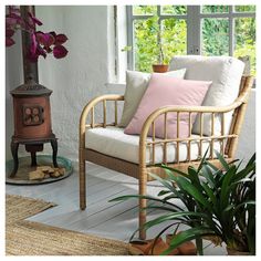 a wicker chair sitting on top of a wooden floor next to a potted plant