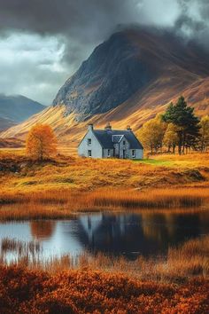 a house sitting on top of a lush green hillside next to a lake and mountains