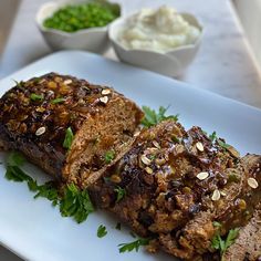 meatloaf on a white plate with garnishes and sauces in small bowls