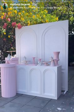 two vases are on display in front of a white cabinet with pink handles and doors