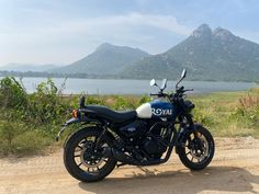 a motorcycle parked on the side of a dirt road next to a body of water