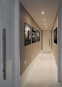 an empty hallway with three pictures on the wall and one door open to another room