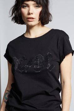 Step into the spotlight in this glittering AC/DC tee. The sleek design features the band's most iconic logo in stunning black crystals that will make you shine like a rock star. Our feminine fitted tee is made with soft cotton fabric, distressed hems, a ribbed crew neckline, and cuffed short sleeves. The design of this style is fitted. For a more standard fit, choose a size up. Details Style #200001 Color: Black Black Crystal AC/DC Logo Fitted T-Shirt Keyword: ACDC 100% Cotton Care/Import Machin Edgy Letter Print T-shirt For Night Out, Black Rhinestone T-shirt For Streetwear, Graphic Cotton T-shirt For Night Out, Edgy Cotton T-shirt For Night Out, Graphic Tee Cotton T-shirt For Night Out, Graphic Cotton Tee For Night Out, Band Logo T-shirt For Concert, Black Cotton T-shirt With Rhinestones, Rocker Style Top For Night Out