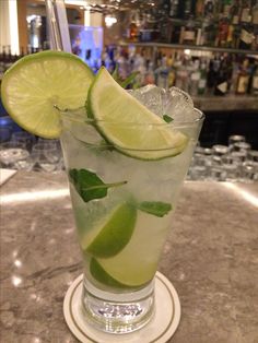 a tall glass filled with ice and lime