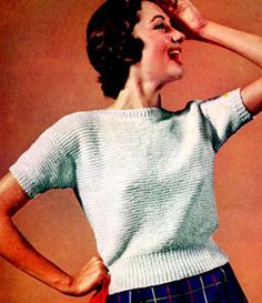 a woman in plaid shorts and a white sweater with her hands on her head looking up