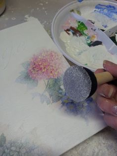 a person is painting flowers on a piece of paper with a paintbrush and brush