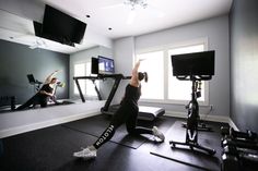 two women in a gym doing exercises on treadmills and television screens behind them