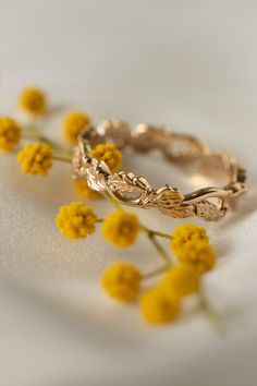 two wedding rings sitting on top of each other with yellow flowers in front of them