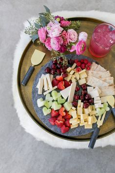 a platter filled with cheese, fruit and flowers