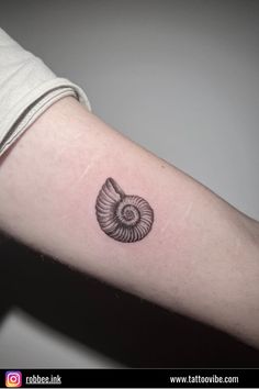 a small black and white tattoo of a shell on the arm