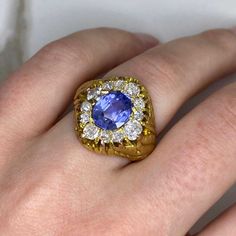 a close up of a person's hand wearing a ring with a blue stone