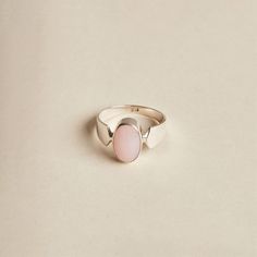 The Pink Opal is a lovely stone to wear. Its soft, baby pink oval cabochon is highlighted by the band's design. The ring is made with 925 sterling silver. The ring is available in size 6 3/4, 7.5, 9, 9.5. Dimensions: Total height: 15mm Total width: 11mm Stone height: 14mm Stone width: 10mm Stone + bezel thickness: 7mm Band width: 8mm to 3mm - Please note - * Additional photos and videos available on request * Go to 'About us' section for links to our socials and website * Only the ring from firs Elegant Pink Opal Oval Jewelry, Elegant Oval Pink Opal Ring, Pink Opal Rings With Gemstone, Pink Opal Gemstone Rings, Oval Pink Opal Gemstone Rings, Classic Pink Ring With Polished Finish, Adjustable Oval Opal Ring Minimalist Style, Oval Pink Opal Ring For Wedding, Classic Pink Cabochon Rings