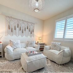 a living room filled with furniture and a chandelier hanging from the ceiling above