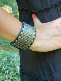 Wide leather cuff bracelet with overlapping flat metal studs for men and women with adjustable snap closure. This bracelet has a modern urban look. Fits wrists from 6.5" to 8.5". Width is about 1.5". Adjustable Punk Cuff Bracelet With Rivets, Punk Adjustable Cuff Bracelet With Rivets, Punk Style Adjustable Cuff Bracelet With Rivets, Punk Cuff Bracelets With Rivets, Edgy Adjustable Cuff Leather Bracelet, Trendy Festival Bracelets With Rivets, Adjustable Rivet Bracelets For Festivals, Adjustable Riveted Bracelets For Festivals, Adjustable Rivets Bracelets For Festival