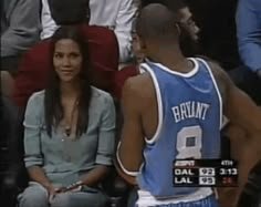 a woman sitting next to a man in a basketball uniform