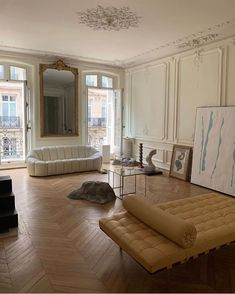 a living room filled with furniture next to windows and a painting hanging on the wall