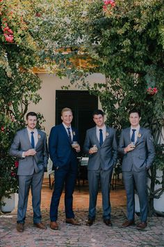 a group of men in suits standing next to each other on a brick floored patio