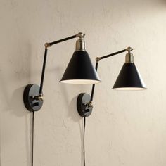 two black and white lamps mounted on the side of a wall next to each other