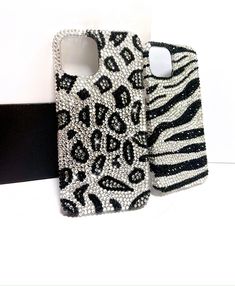 two cell phones that are next to each other on a white surface with zebra print