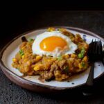 a white plate topped with fried eggs and hashbrowns next to a fork