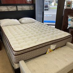 a mattress and footstool are on display at a store in front of a window