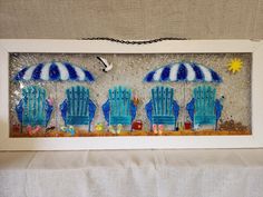 three blue beach chairs with umbrellas on the sand