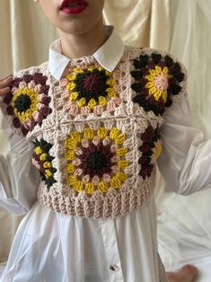 a woman is wearing a crocheted vest with sunflowers on it