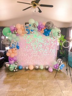 a room filled with balloons and decorations on top of a tiled floor next to a ceiling fan