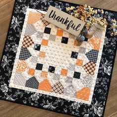 a quilted thank you sign on top of a wooden table next to some flowers