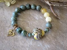 a close up of a bracelet on a table next to flowers and a vase with yellow flowers