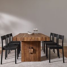 a wooden table with four black chairs and a wine glass on the top one is empty