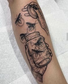 a person with a tattoo on their arm holding a jar filled with honeybees