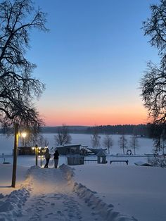 two people are walking in the snow at dusk