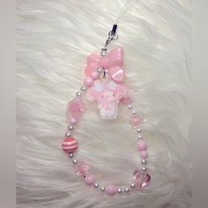 a pink and white necklace with a bow on it's end is laying on a furry surface