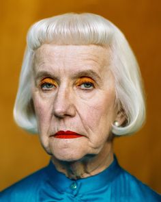 an older woman with white hair and orange eyeshadow, wearing a blue shirt