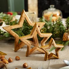 two wooden stars sitting on top of a table next to silverware and christmas decorations