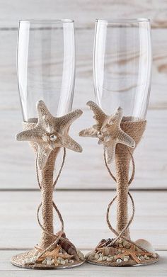 two wine glasses decorated with starfishs and seashells are sitting next to each other